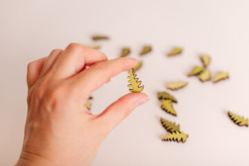 A hand holding small decorative wooden pieces shaped like leaves, perfect for craft projects