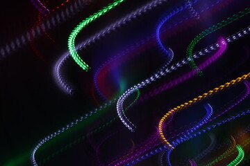 Una toma de cerca de varias luces de colores en movimiento en la oscuridad. Movimiento de cámara  © Elika R