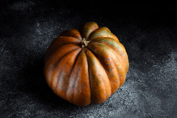 Fresh pumpkin on a dark background. Textured orange pumpkin. Autumn harvest. Ingredient for pumpkin...