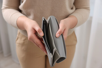 Fototapeta premium Woman with empty wallet indoors, closeup view