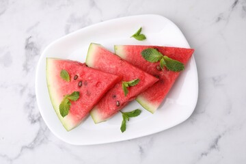 Fresh watermelon slices with mint leaves on white marble table, top view