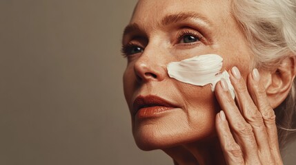 Senior woman with white cream on cheek.  Skincare beauty advertising