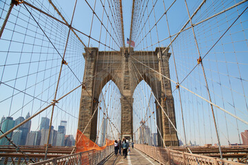 Walking the Brooklyn Bridge over the river and into Manhattan in New York USA on a spring day
