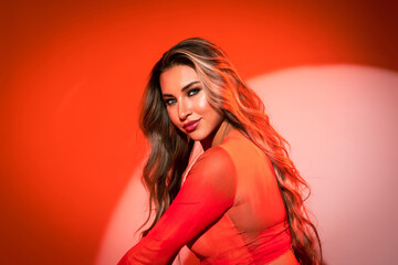 Close-up of a model on an orange background in a blouse with an expressive and penetrating gaze....