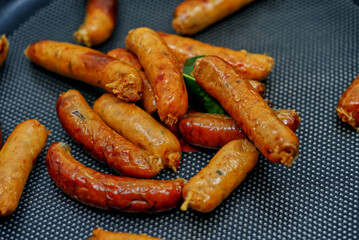 Sai Oua, the traditional Thai Northern sausage, the small size type of Sai Oua on black a  pan fry, pile of Thai northern sausages, close up food image.