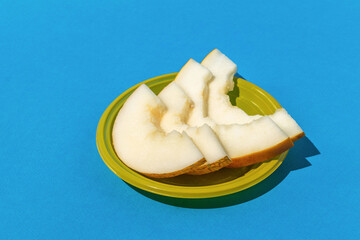Fresh Sliced Melon in Yellow Bowl on Bright Blue Background