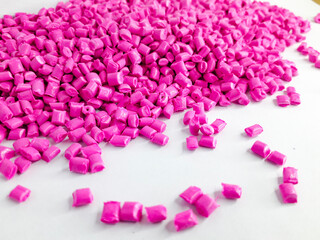 Neon pink masterbatch granules on white background. Color pigment carrier polymer in plastic industry