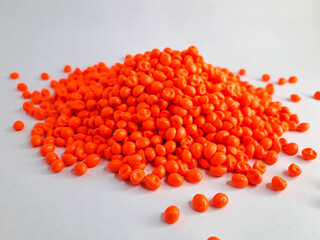 Neon orange masterbatch granules on white background. Color pigment carrier polymer in plastic industry