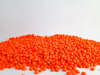 Neon orange masterbatch granules on white background. Color pigment carrier polymer in plastic industry