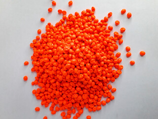 Neon orange masterbatch granules on white background. Color pigment carrier polymer in plastic...