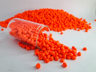 Neon orange masterbatch granules on white background. Color pigment carrier polymer in plastic industry