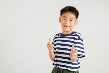 Cheerful Asian young kid boy excitedly makes two gun finger gesture to the camera with a friendly and cheeky expression. Isolated on white background, primary child exudes positivity and joy