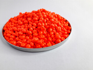 Neon orange masterbatch granules on white background. Color pigment carrier polymer in plastic industry
