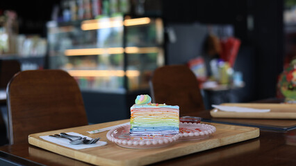 Close-up rainbow crepe cake slice on a beautiful plate.Crepe cake for dessert menu in a coffee shop. Crepe Cake with rainbow colors