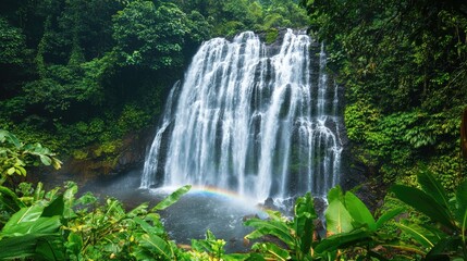 Fototapeta premium Breathtaking waterfall landscape with cascading water, lush green surroundings, and a rainbow, perfect for nature themes