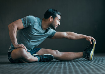 Stretching legs, fitness and man on floor for exercise, training and warm up for athlete workout. Health, sports and person with muscles for wellness, performance and flexibility on gray background