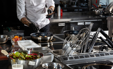 Professional chef cooks shrimps in frying pan with olive oil in restaurant kitchen