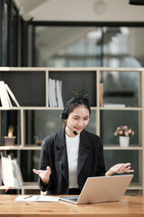 Fototapeta premium A woman wearing a headset is talking on a laptop