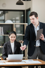 A man and a woman are standing in front of a laptop computer