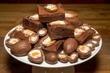 A plate of delicious chocolate cream easter egg brownies, chocolate easter eggs treats on a wooden kitchen table