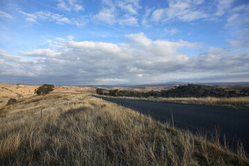 View of rural landscape and aeroplane vapour or contrails crossing the blue sky overhead in rural New South Wales, Australia
