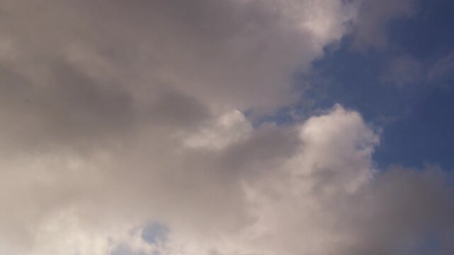 Time lapse video of rain clouds moving in a blue sky