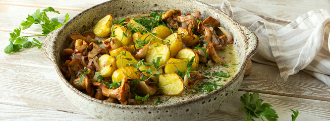 ceramic dish with baked potatoes with chanterelles on light wooden table © kochabamba