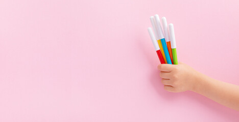Child hand holding colorful markers for painting top view. Toddler development, leisure activity...
