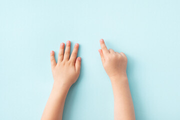 Small child hands on blue background top view. Skin care, family, playing and education template concept.