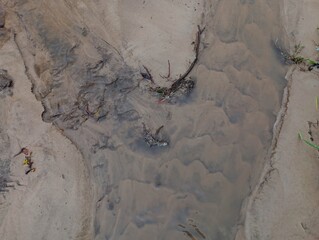 The gray background of a dirt road after rain, along which a stream of rainwater flows. Wet dirt road after rain.