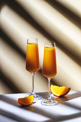 Summer orange cocktail drink with juice and dry champagne or sparkling wine. Beige background, hard light