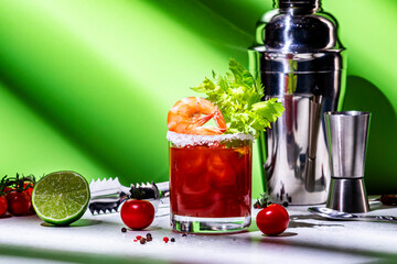 Bloody Mary cocktail variation with tomato juice, vodka, clam broth, celery, hot sauce and ice. Green background, hard light