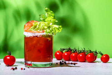 Bloody Mary cocktail variation with tomato juice, vodka, clam broth, celery, hot sauce and ice. Green background, hard light