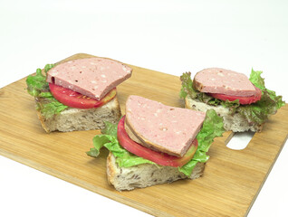 Sandwiches, ham sandwiches, lettuce leaves, tomato slices, whole grain bread, on a wooden board, healthy breakfast food.
