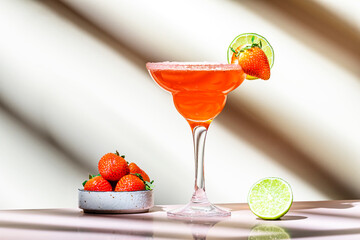 Strawberry summer red cocktail drink with tequila, limу juice, liqueur, berries and ice in glass. Beige background., hard light
