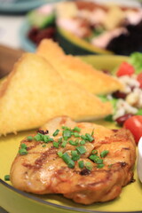 Grilled chicken breast served with crispy French fries, a fresh salad, and a side of tangy barbecue sauce is perfect for food lovers and culinary enthusiasts.