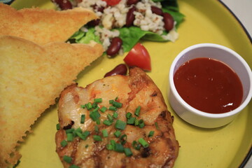 Grilled chicken breast served with crispy French fries, a fresh salad, and a side of tangy barbecue sauce is perfect for food lovers and culinary enthusiasts.