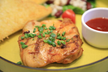 Grilled chicken breast served with crispy French fries, a fresh salad, and a side of tangy barbecue sauce is perfect for food lovers and culinary enthusiasts.