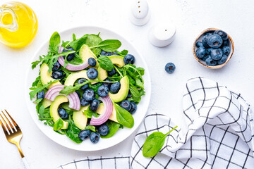 Мegan salad with blueberry, avocado, onion, spinach and arugula, white background, top view