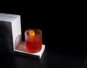 Ruby red cocktail in glittery glass with orange garnish