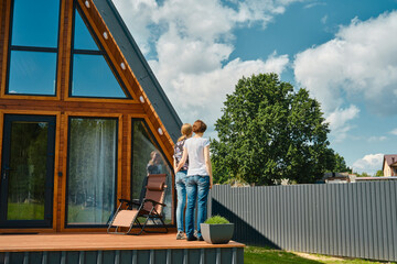 Back side view of two women standing on terrace of tiny house