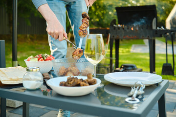 Unrecognizable man removes kebab from skewer