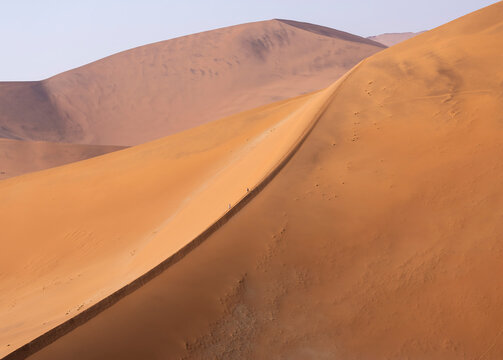 Expansive sand dunes with tiny figures in Namibia, Africa