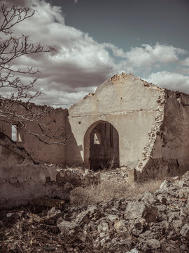 Crumbling walls of a forsaken structure under cloudy skies