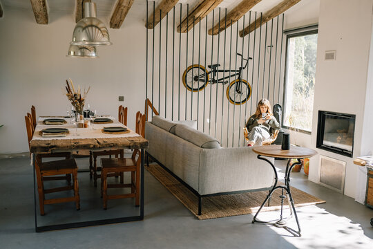 Woman relaxing in living room with rustic dining setup
