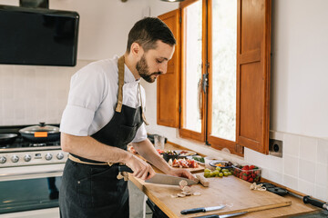 Private chef preparing sausages in kitchen, focusing on task