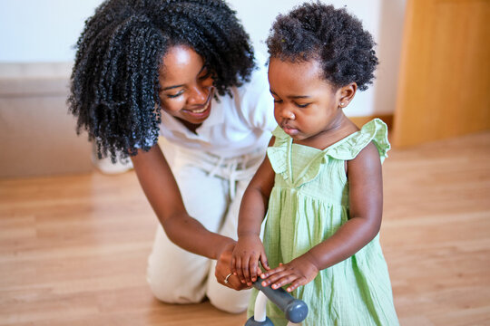 African American mother teaches daughter to walk indoors