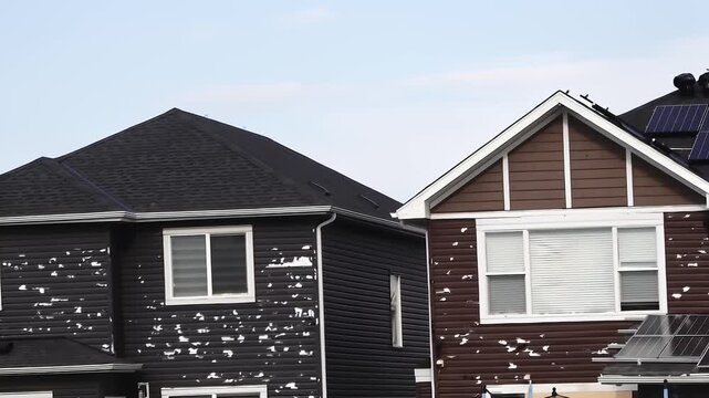 Homes with extensive hail damage, where substantial portions of vinyl siding are missing, revealing the underlying structure.