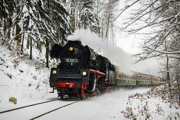 German steam express locomotive driving through a snowy family