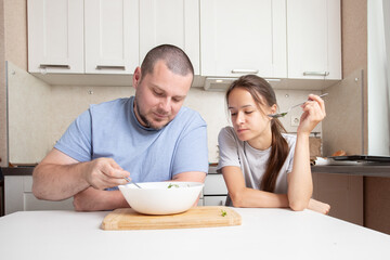 Teenage girl and father eating together, kitchen joy, father and daughter sharing food.